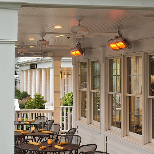 This image shows the outdoor seating area of Wild Goose Tavern, with tables, chairs, ceiling fans, and heaters, along with its sign prominently displayed.