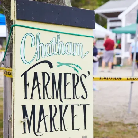A sign at a market reads &ldquo;Chatham Farmers&rsquo; Market&rdquo; in large teal and black letters.