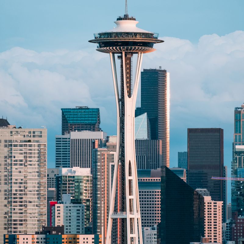 The image features the Space Needle, a famous landmark, against a backdrop of modern high-rise buildings in Seattle, Washington, USA.